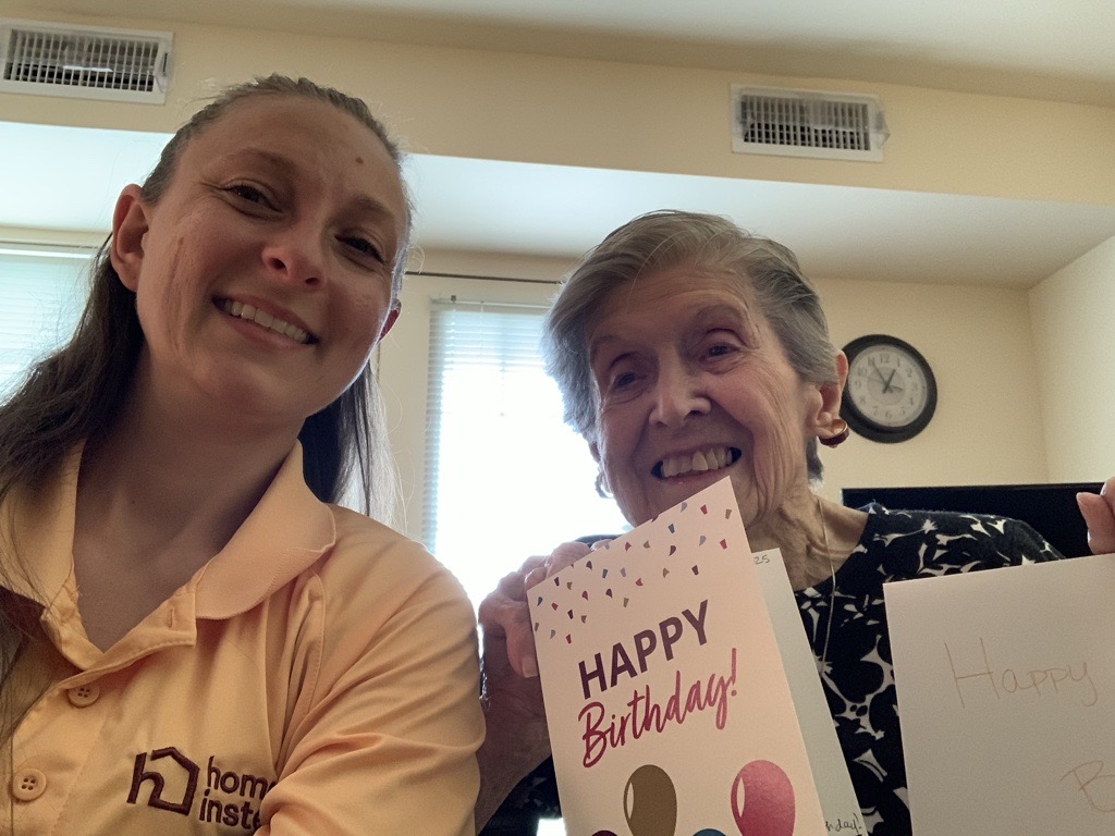 Caregiver celebrating a 100th birthday with an older adult, supporting meaningful moments at home.