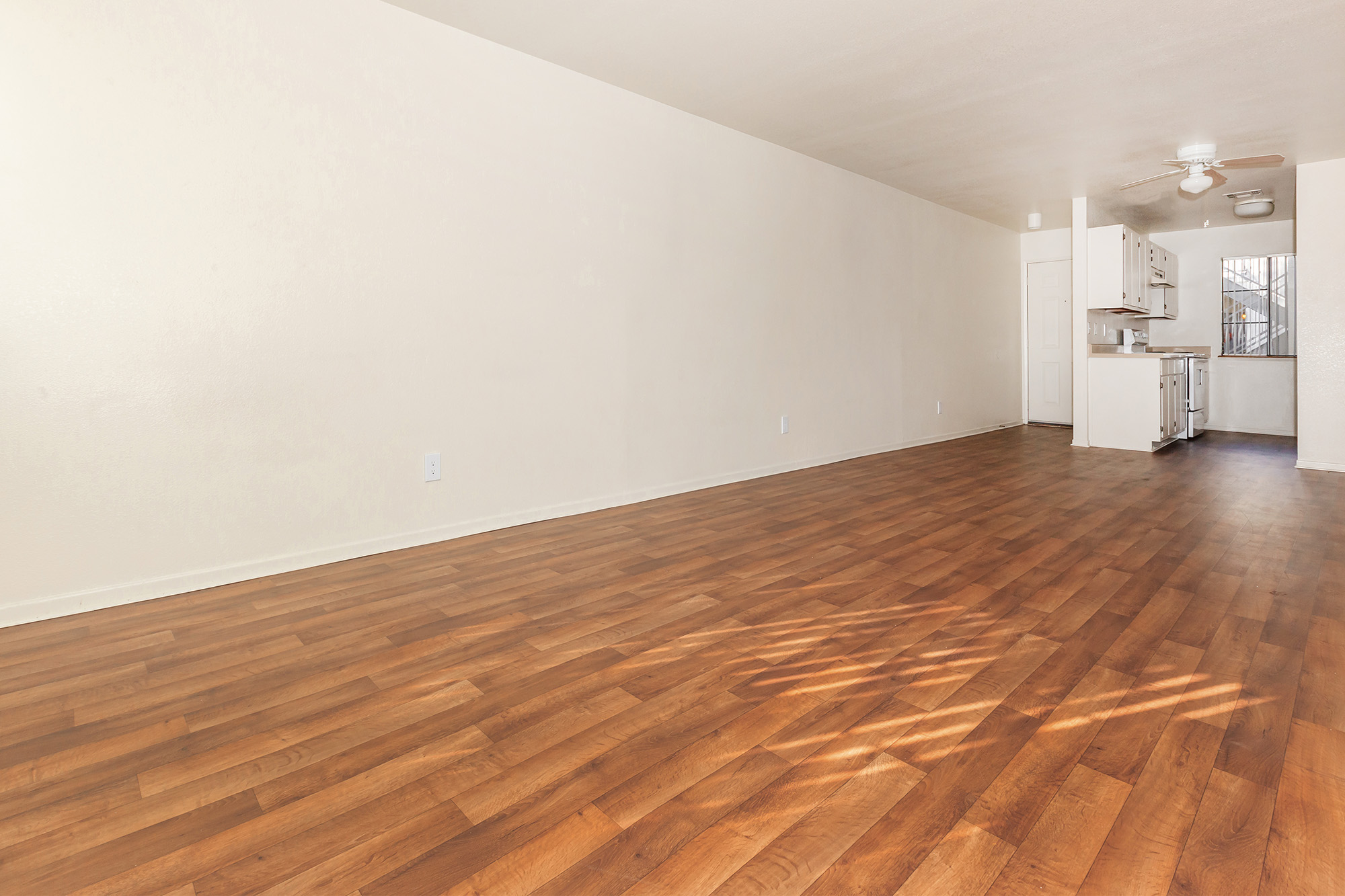 Living room with wood-style plank flooring and view to kitchen area.