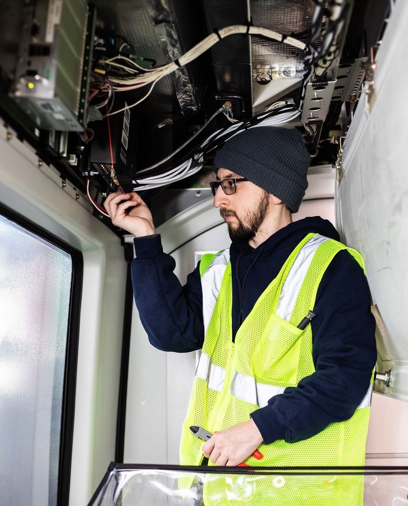 SimpleCom Network technician working on communications equipment and network cabling inside a mobile vehicle installation