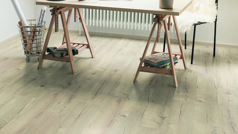 Light coloured wood effect laminate flooring in a room with a painting table set up.