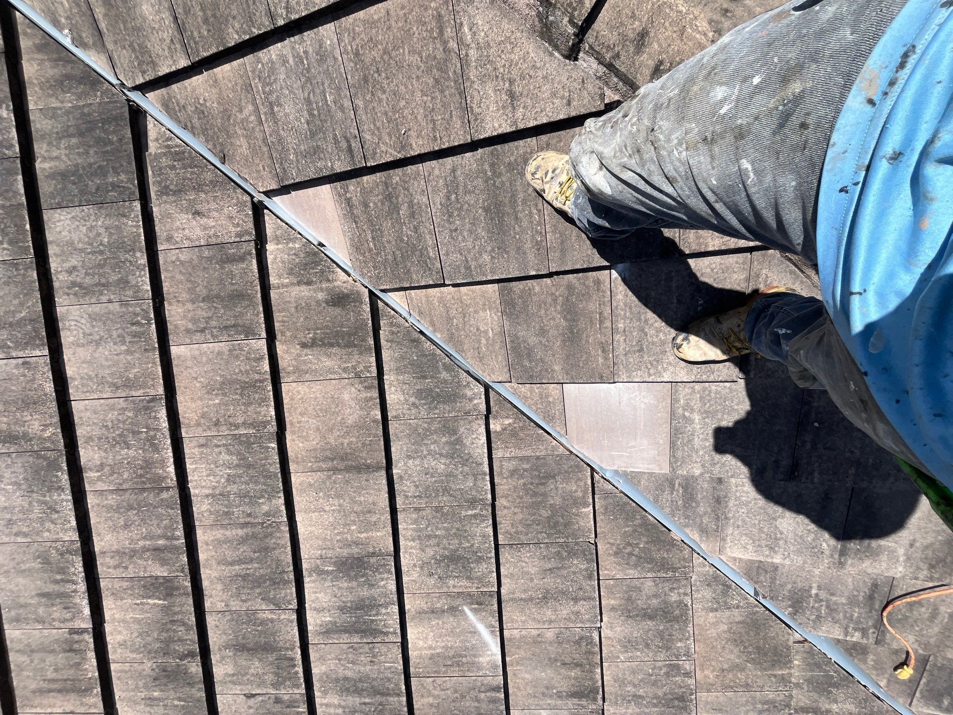 Roofer working on a tile roof section, showing hands-on inspection and repair work for a residential 