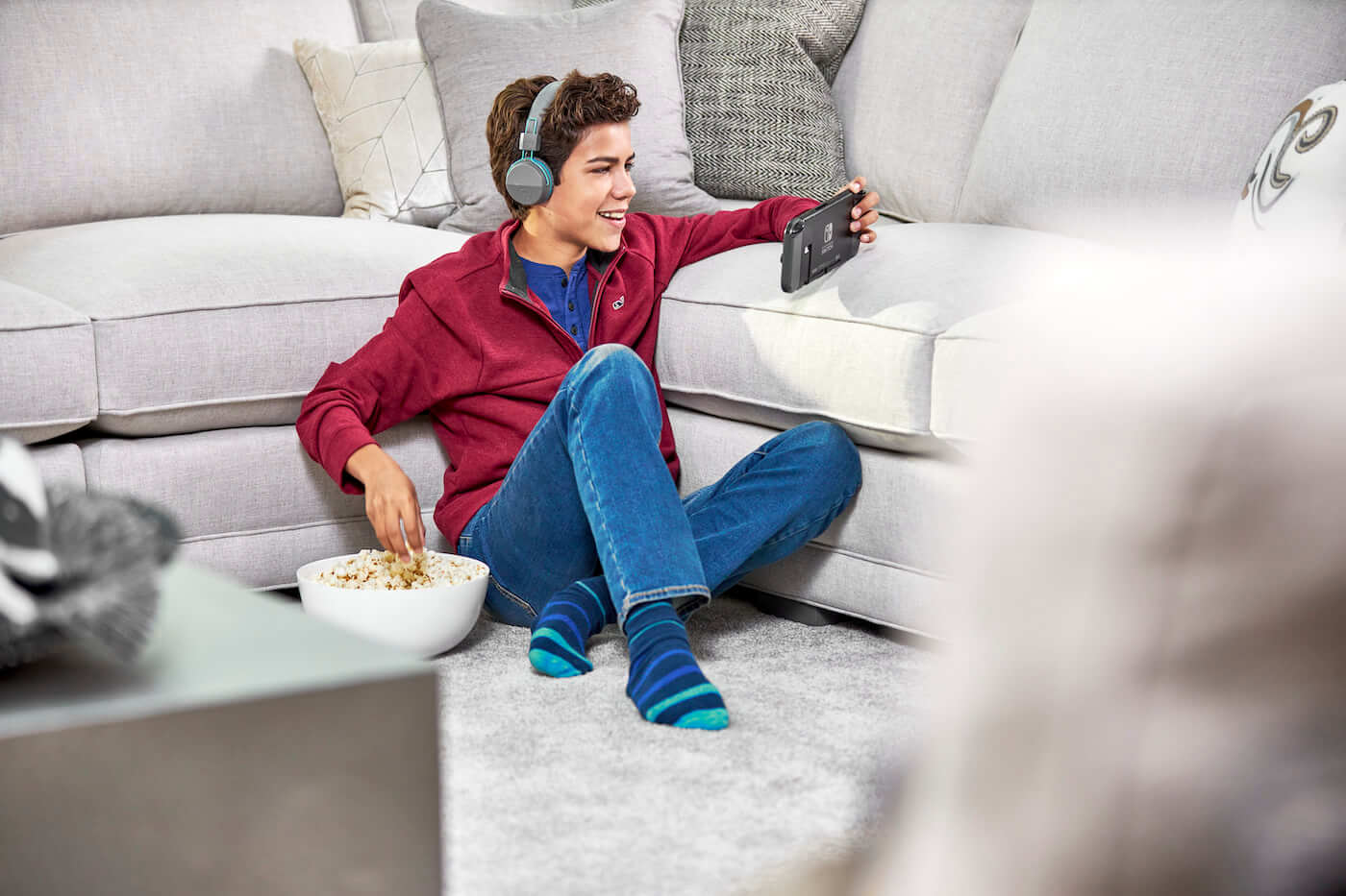Boy playing video game on carpet next to couch