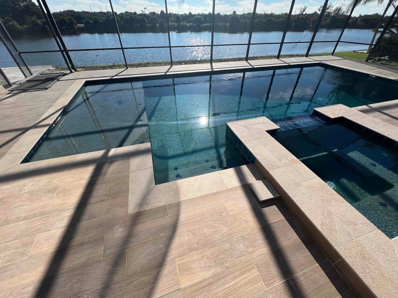 Screen-enclosed backyard swimming pool with an attached spa, spacious deck, and protected outdoor living area.