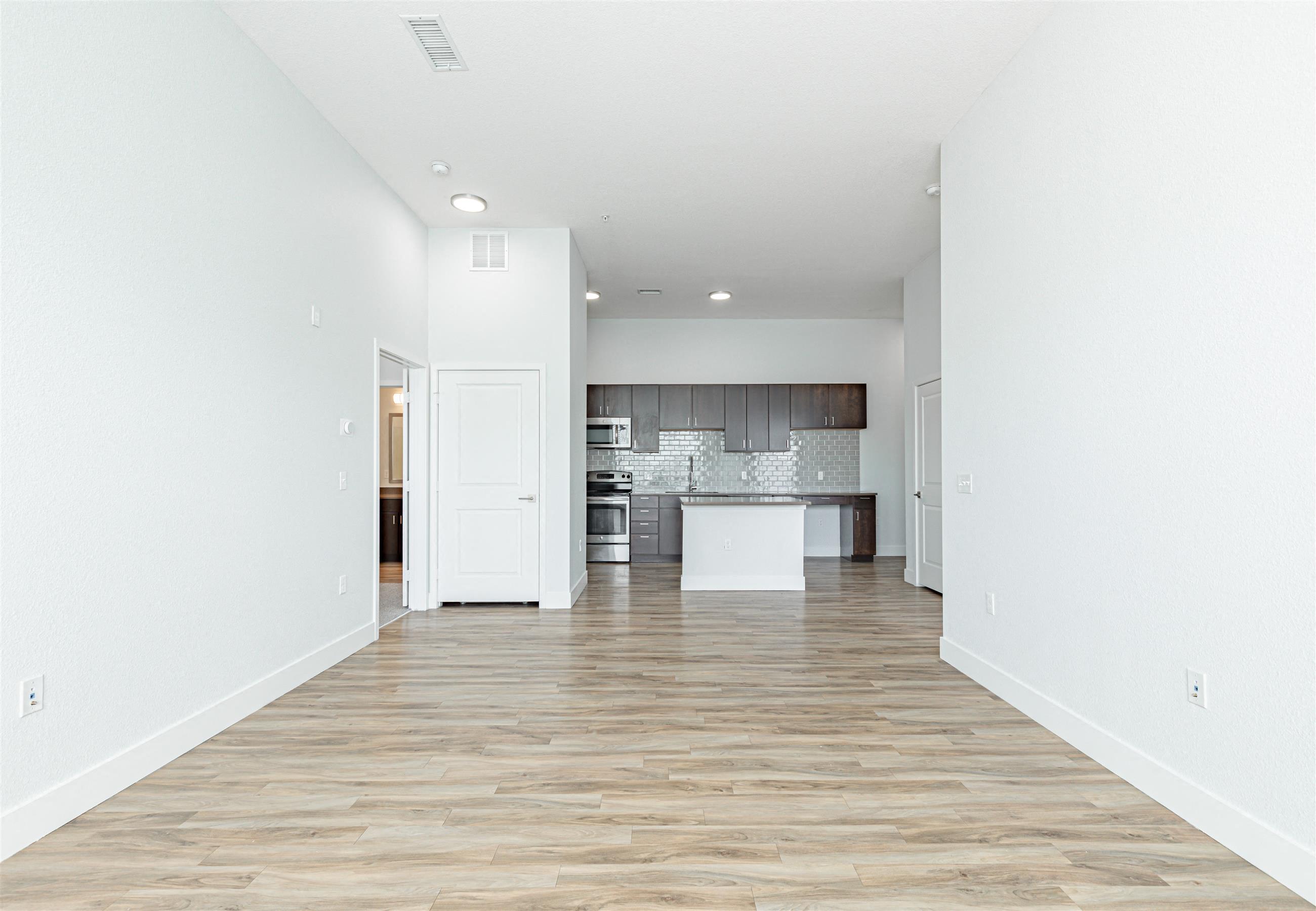 a spacious living room with a kitchen in the background