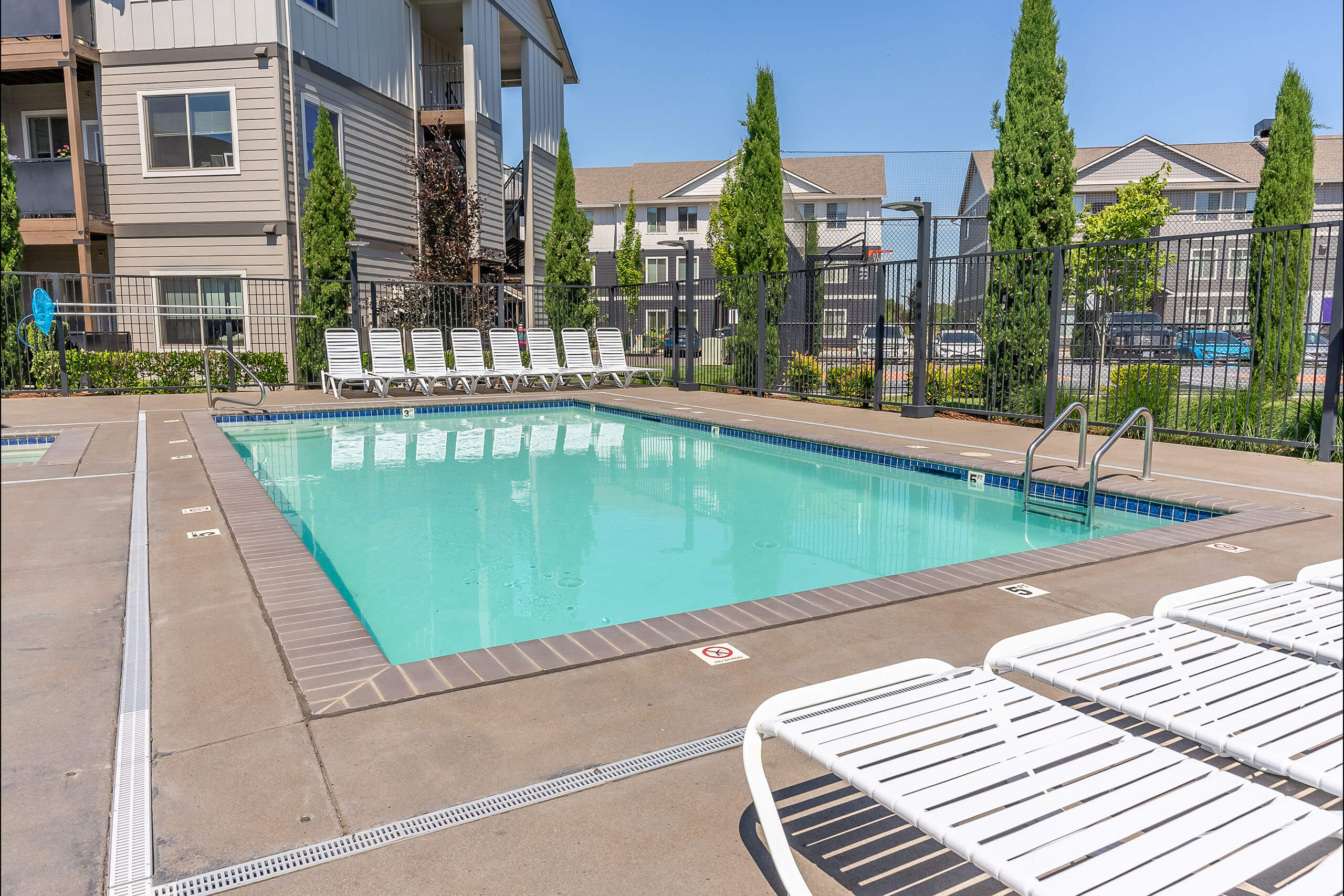 A swimming pool surrounded by white lounge chairs.