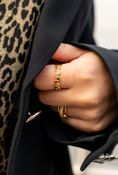 A gold-toned ring with multicolored stones adds a playful accent to a black blazer and leopard print. Discover jewelry for daily styling and special gifts at Eliana Curated in Old Town Alexandria, VA.