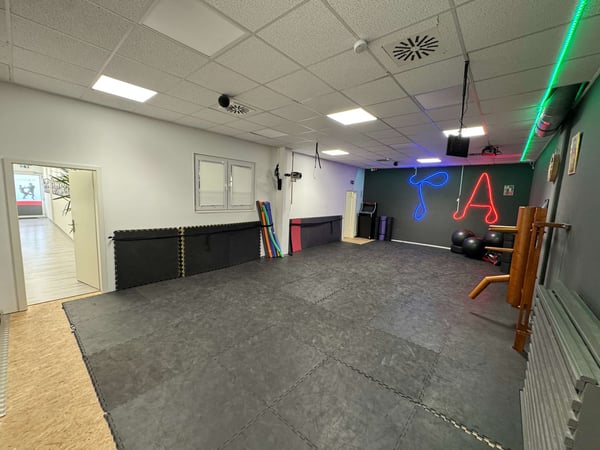 TA WingTsun Seelze - Professioneller Kampfkunst-Trainingsraum mit freier Bodenfläche, Neonwand, Deckenbeleuchtung und spezieller Ausstattung für Technik, Koordination und Partnerübungen.