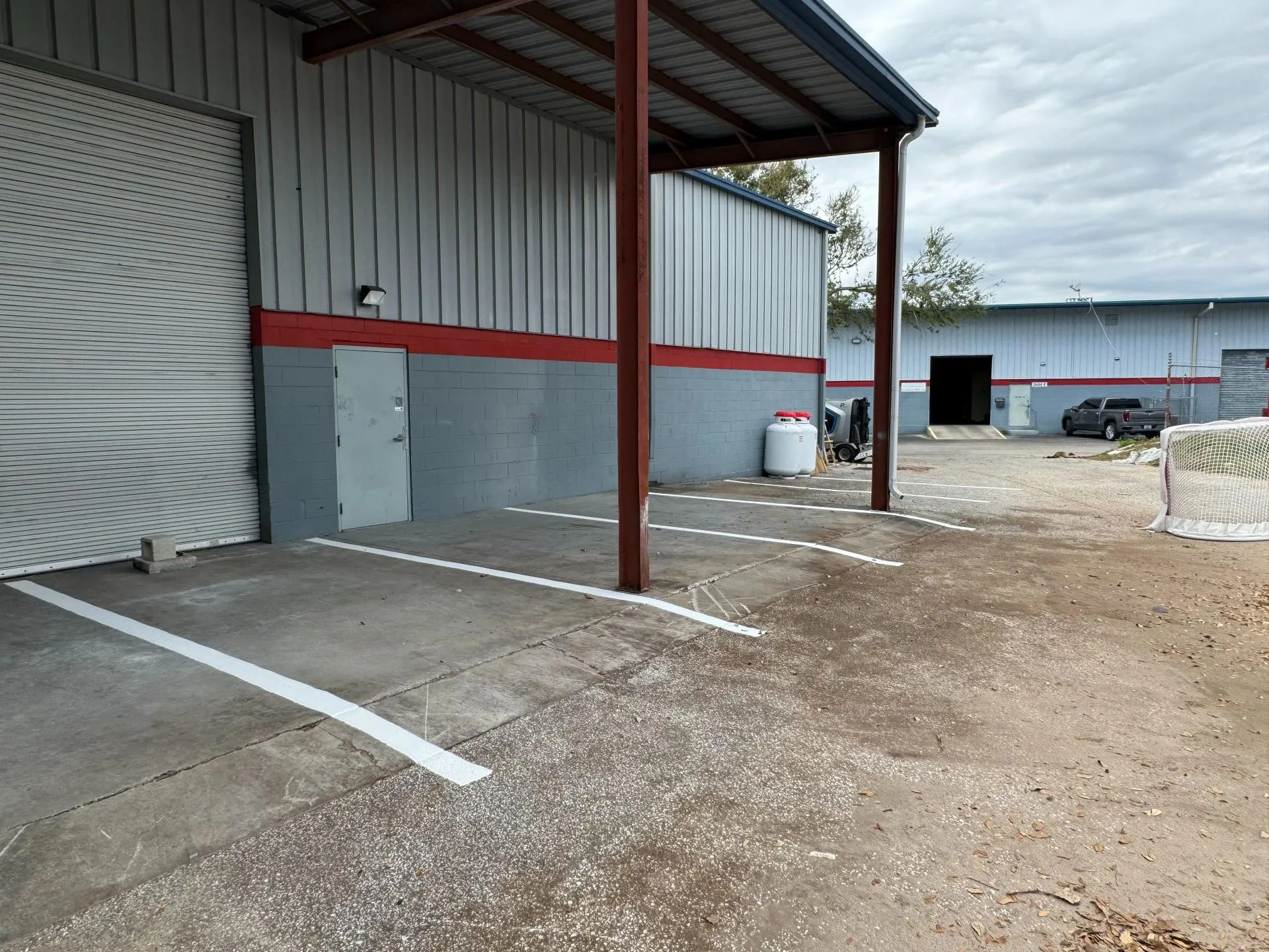 Industrial warehouse property featuring newly painted parking stalls and loading area markings for organized vehicle parking and site management.