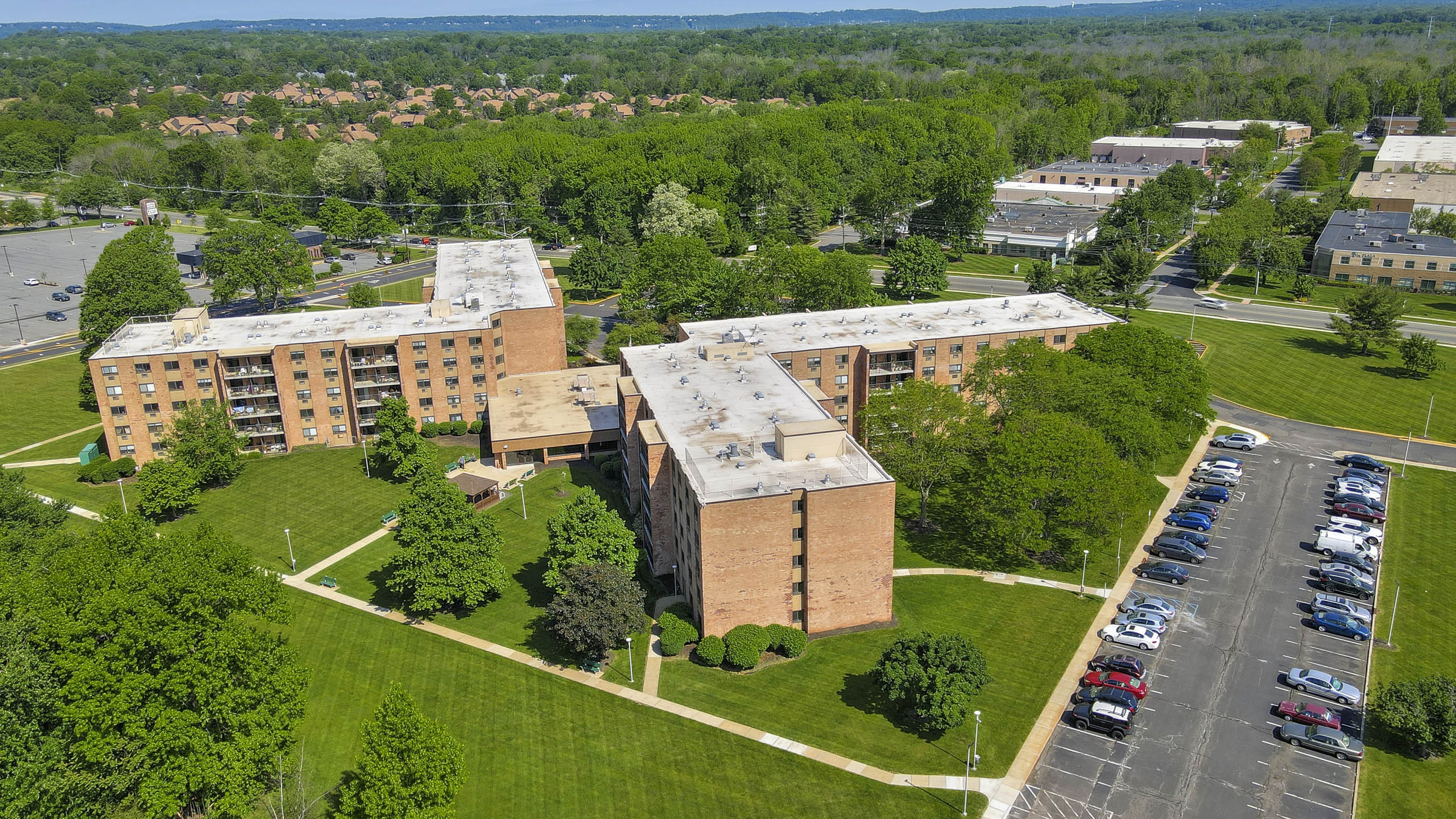 A parking lot is in front of a building with a green lawn in between.