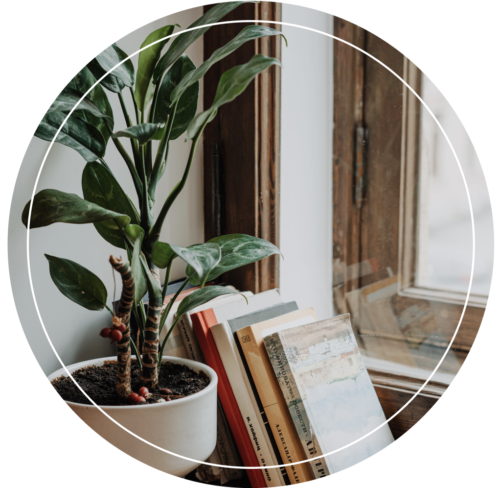 A pile of books by a windowsill.
