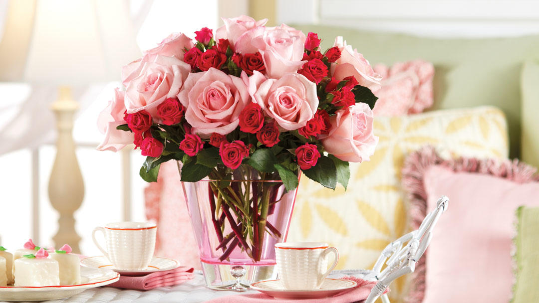 A stunning bouquet of pink roses and red spray roses elegantly arranged in a pink glass vase. Perfect for gifting on Valentine's Day, anniversaries, or as a thoughtful gesture to brighten someone’s day.
