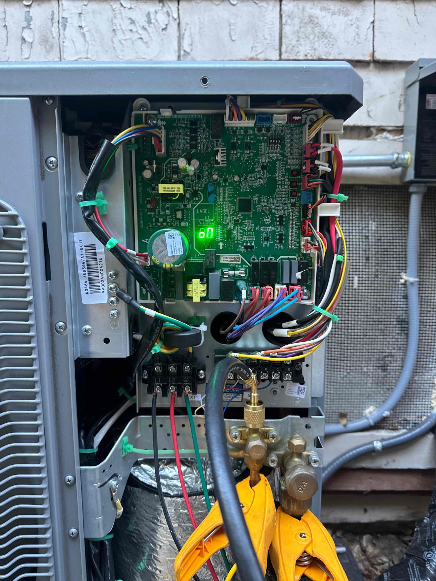 An Affordable Heating and Air technician works on an AC unit's control board and refrigerant lines during a system installation or repair in Ventura County.
