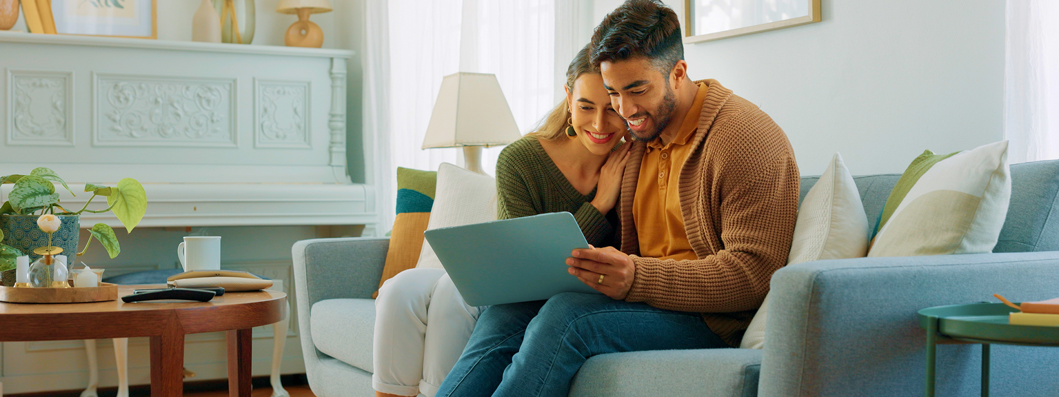 A couple on the couch looking at their iPad.