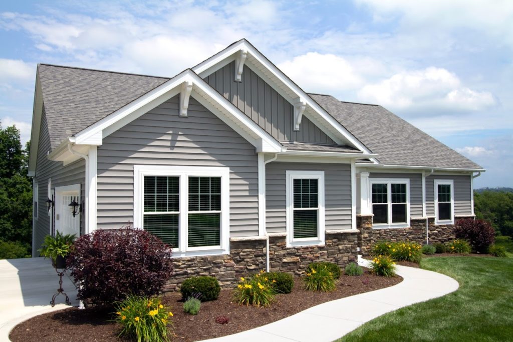 The EcoTek 3200 Series Windows on this home enhance the clean, modern gray siding and stone facade look. These windows provide a perfect blend of style and energy efficiency, creating a bright, welcoming appearance that complements the home's design.