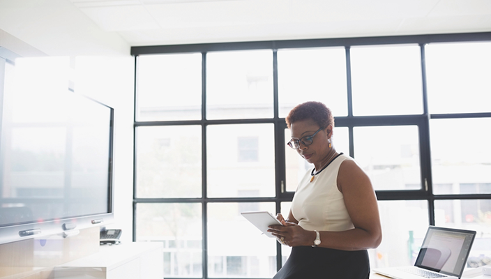 A woman looking at her tablet while seated in an office.