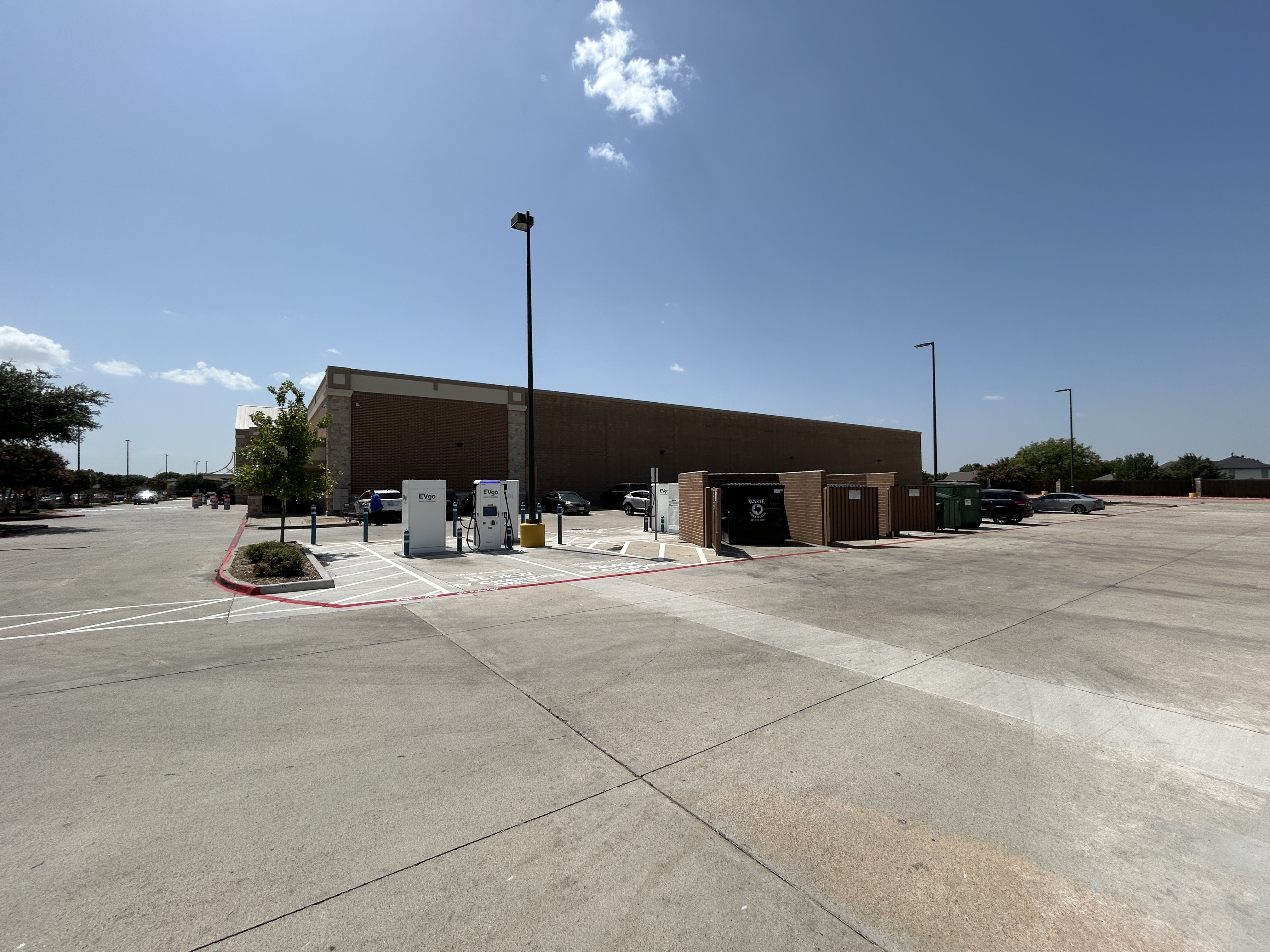 Several EVgo fast charging units installed in marked parking spaces at a public charging station, wi 