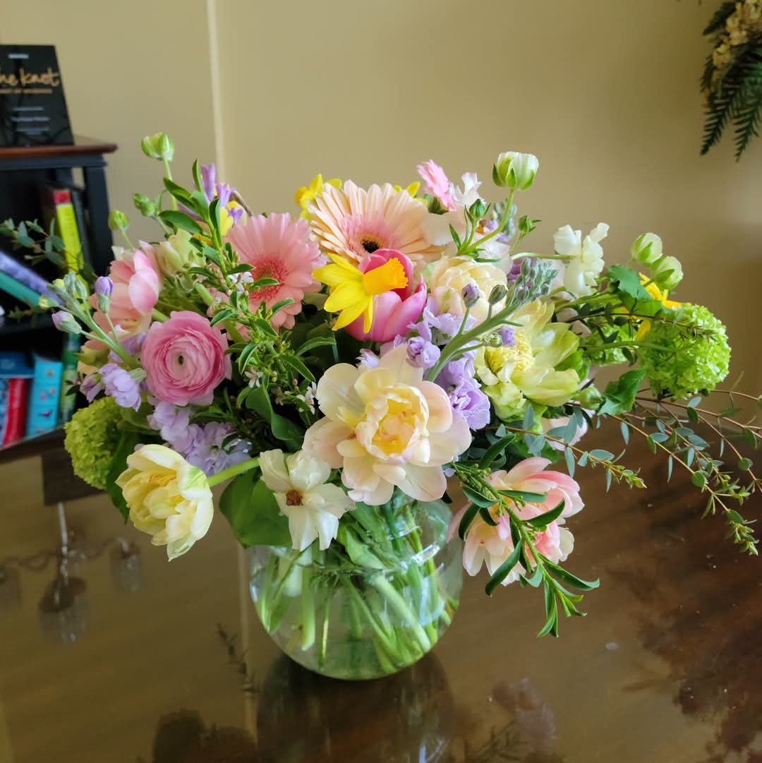 Lush spring garden vase arrangement with tulips, ranunculus, viburnum, butterfly ranunculus, mini daffodils, stock, and eucalyptus.