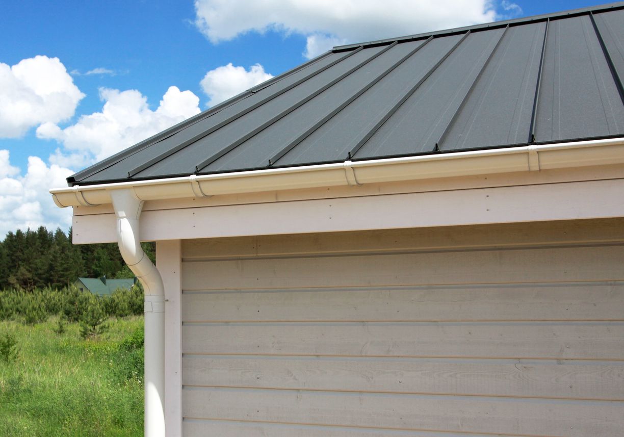 A close exterior view highlights a dark standing-seam metal roof, light-colored fascia, white gutter 