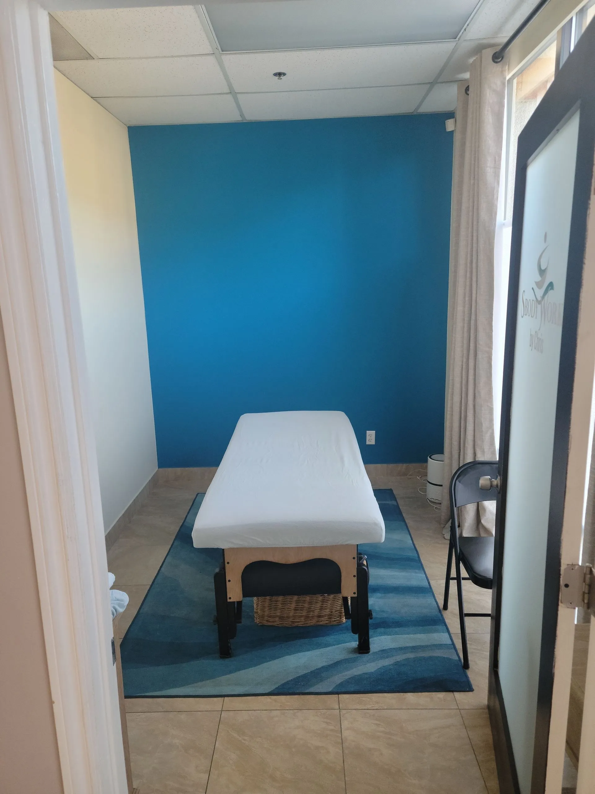 Clean and welcoming massage therapy room featuring a professional treatment table, calming blue acce 