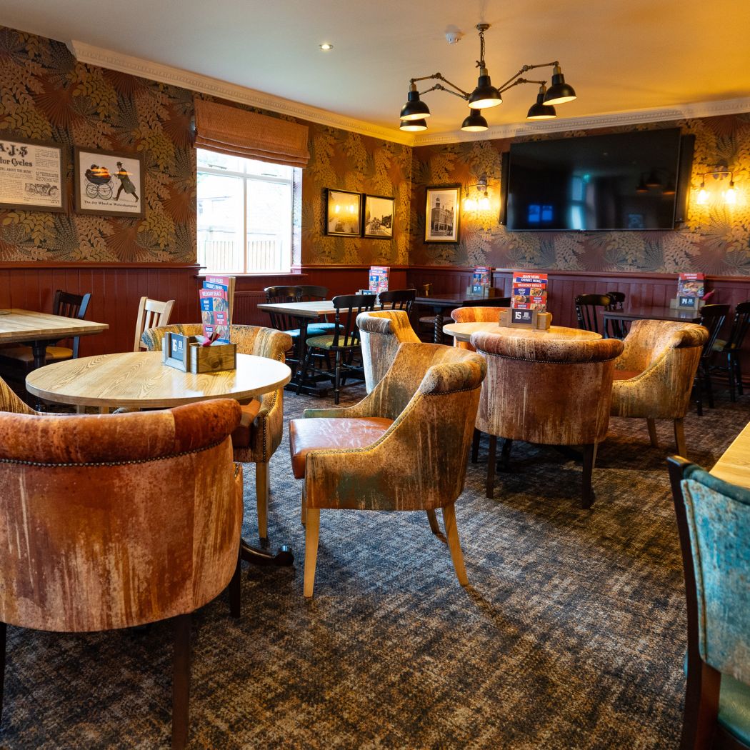 Comfortable dining area with upholstered chairs, patterned walls and a large screen, ideal for relaxed meals and social gatherings.