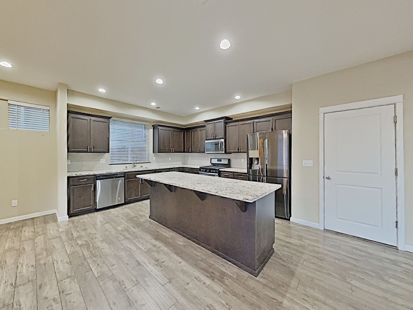 Kitchen with luxury vinyl plank flooring, granite countertops, stainless-steel appliances and a large island at Invitation Homes Seattle.