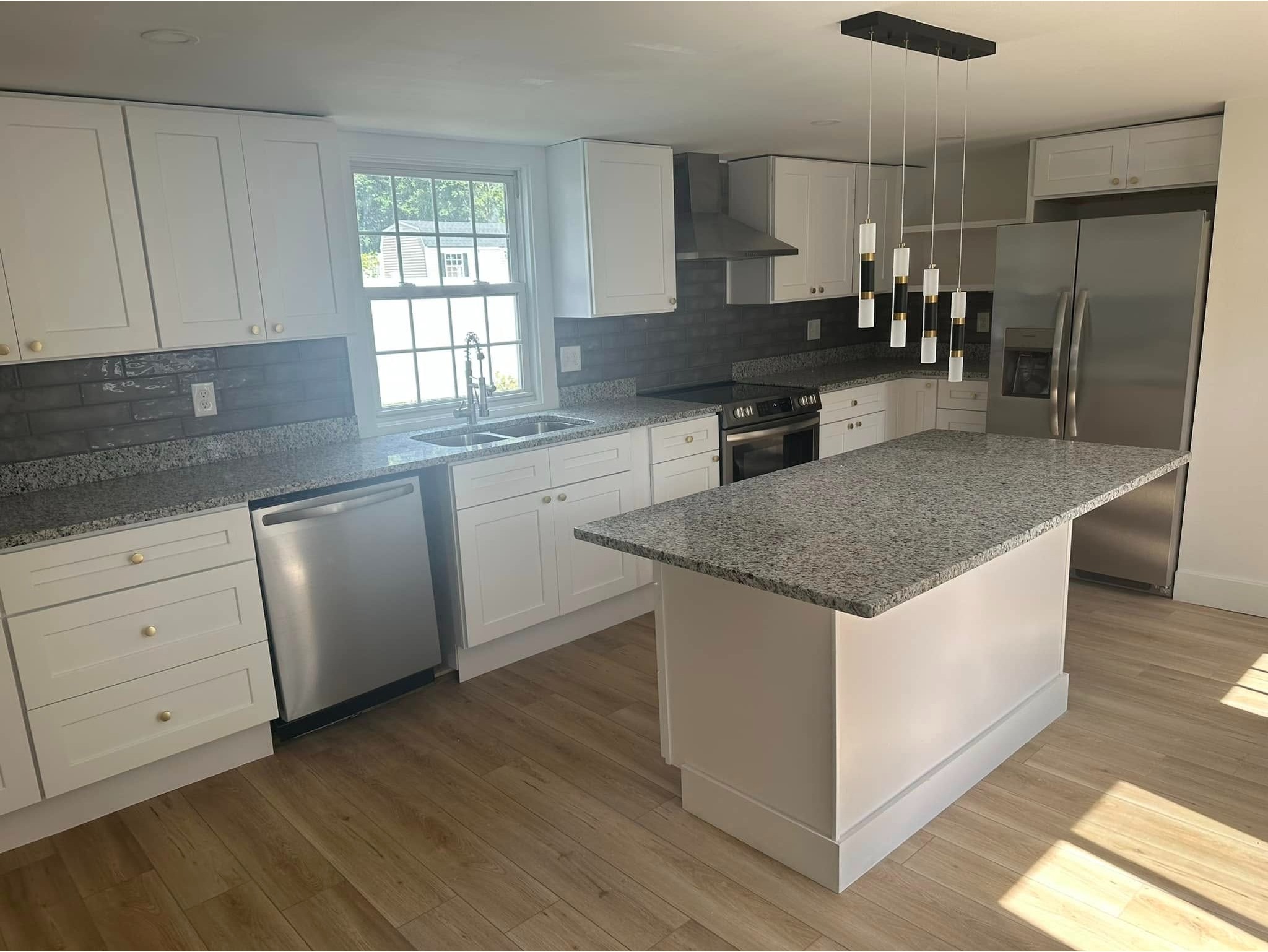 Remodelación de cocina moderna con gabinetes blancos estilo shaker, encimeras e isla central de gran 