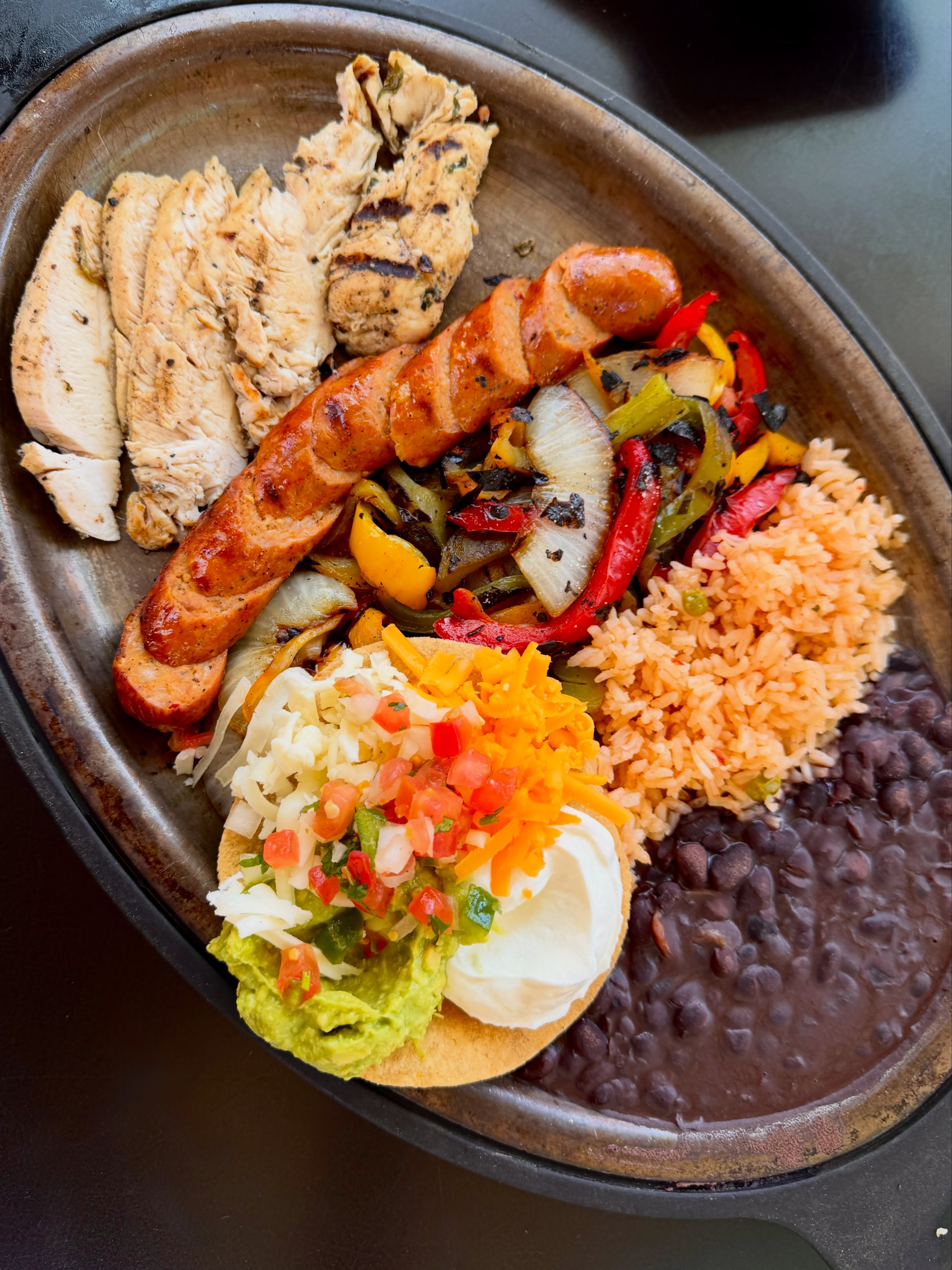 We took a dang good fajita and gave it a little Texas backbone.
Our new Chicken & Sausage Fajitas bring flame-grilled chicken and Texas hot link sausage together with peppers, onions, rice, beans, pico, guac, sour cream, cheese, and house-made tortillas.
Order it for one, or make it for two to share. A little smoky, a little spicy, and exactly the kind of fajita summer called for.
