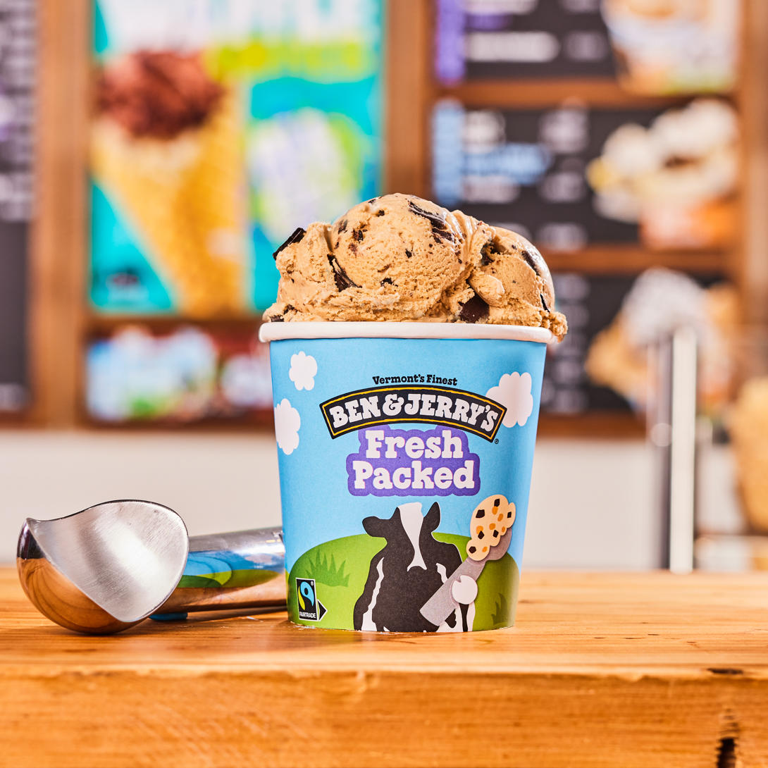 Fresh packed pint in front of Ben & Jerry's ice cream shop menu board. Ben & Jerry’s Manchester (603)647-9400