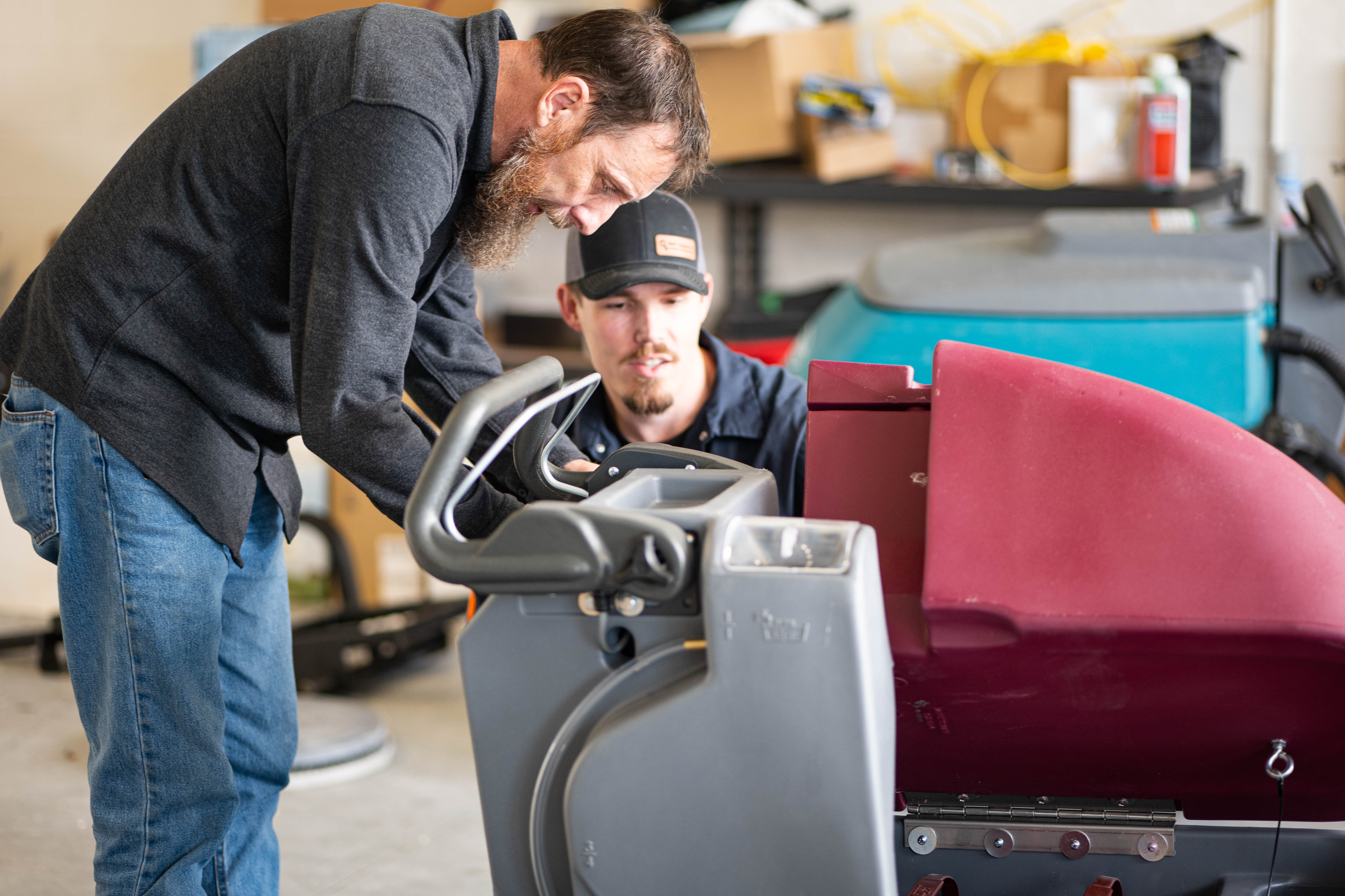 A WaySolutions service technician consults with a facility manager over the control panel of a Minuteman E20 walk-behind floor scrubber. We believe in transparent service and hands-on operational training, ensuring our commercial clients in Layton, Utah, fully understand their equipment's maintenance needs, operational health, and preventative care schedules.