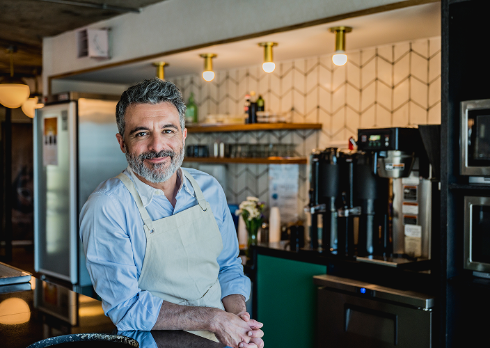 A business owner posing in his restaurant.