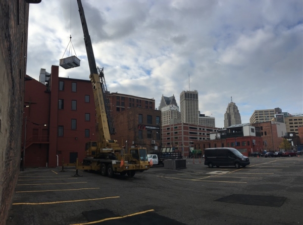 Crane lifting rooftop equipment at a downtown client job site