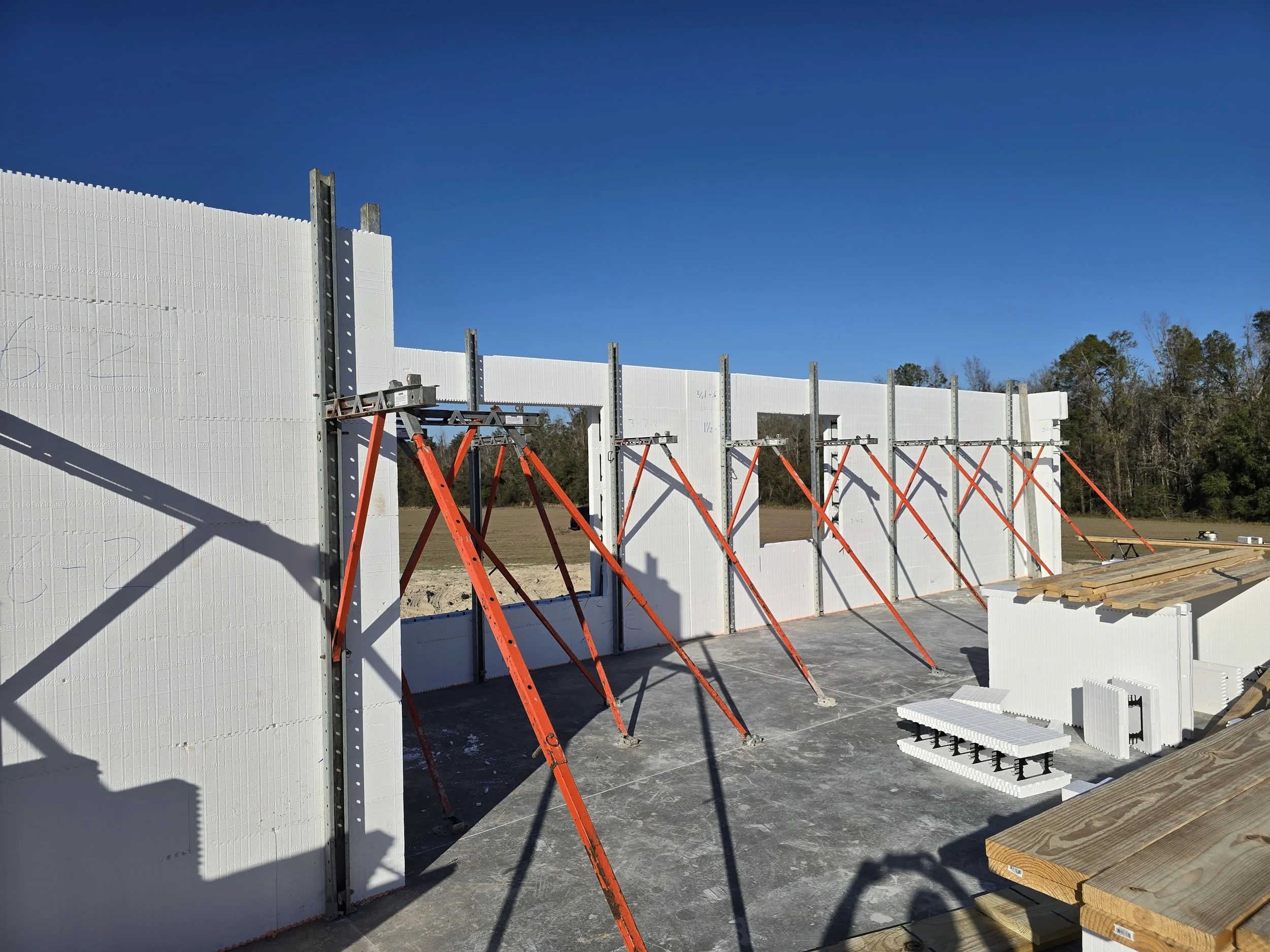 A construction site is shown under a clear blue sky. The image features the partially constructed wa 