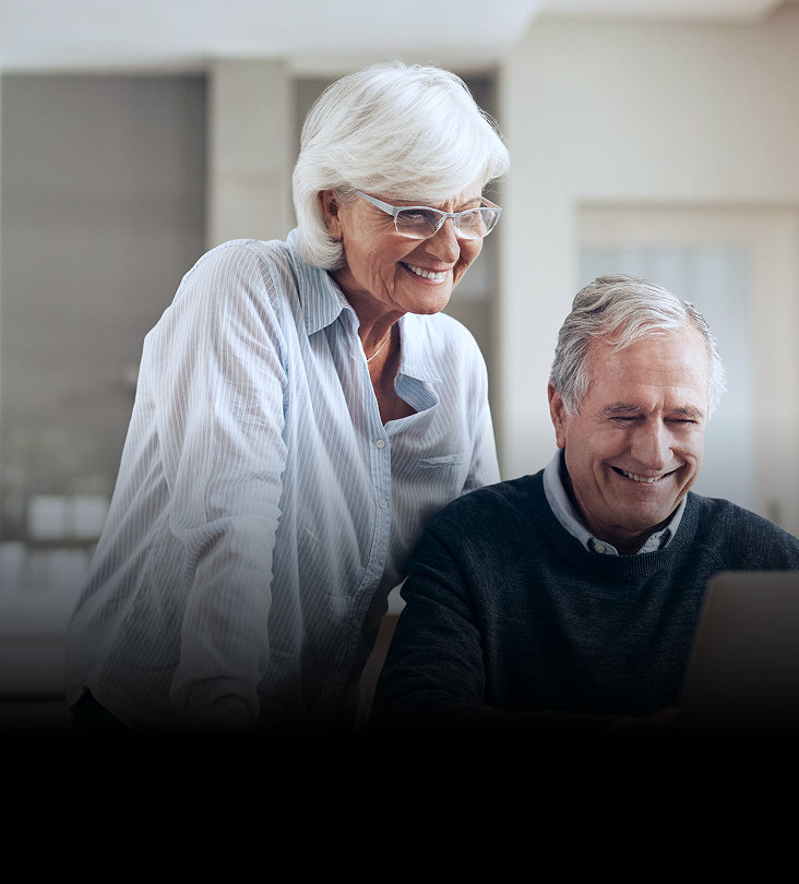 An elderly couple reviewing their accounts on their laptop.