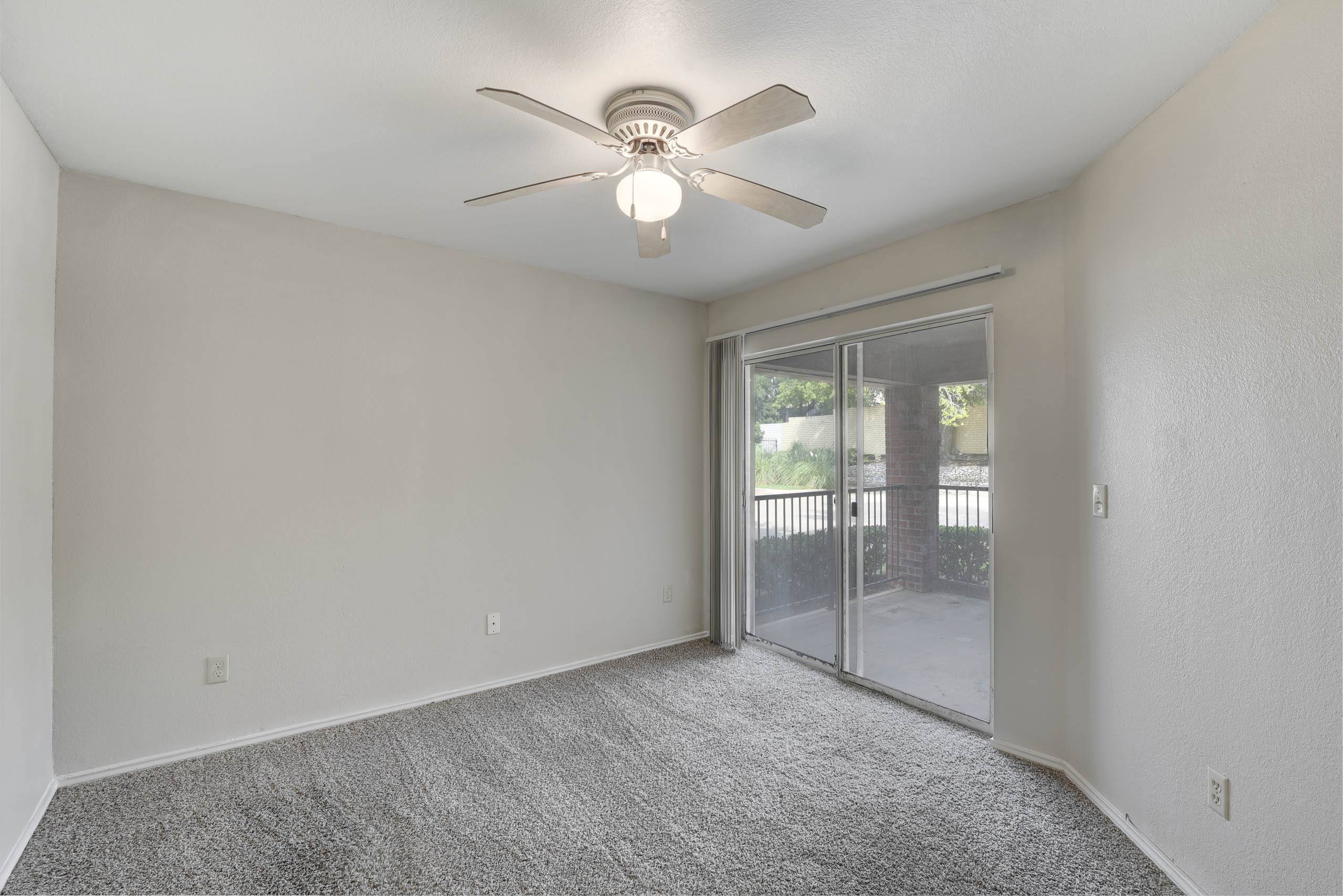 A room with a ceiling fan and carpeted floor.