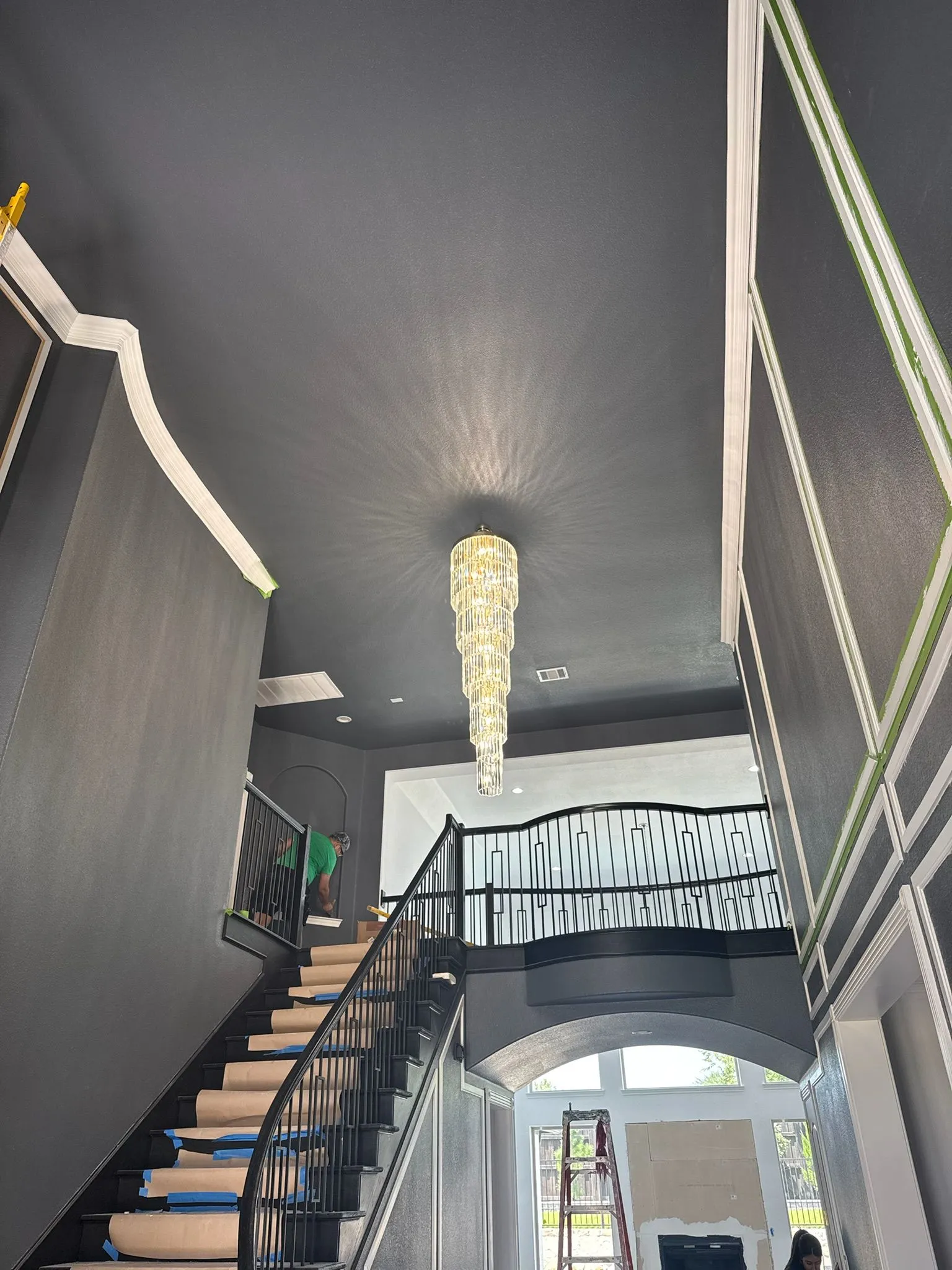 Completed chandelier or decorative light fixture installation in a high-ceiling stairway by Tier One Electric.