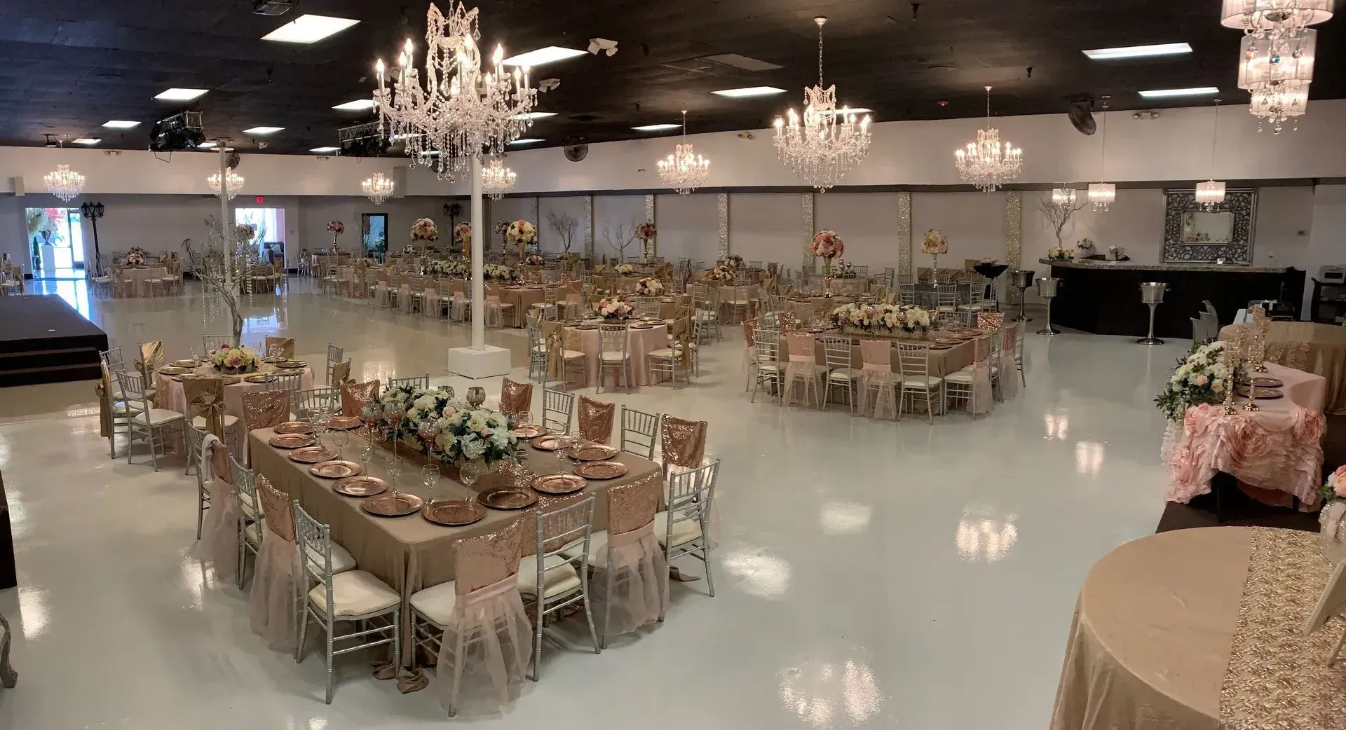 Expansive ballroom featuring crystal chandeliers, floral centerpieces, banquet tables, polished floo 