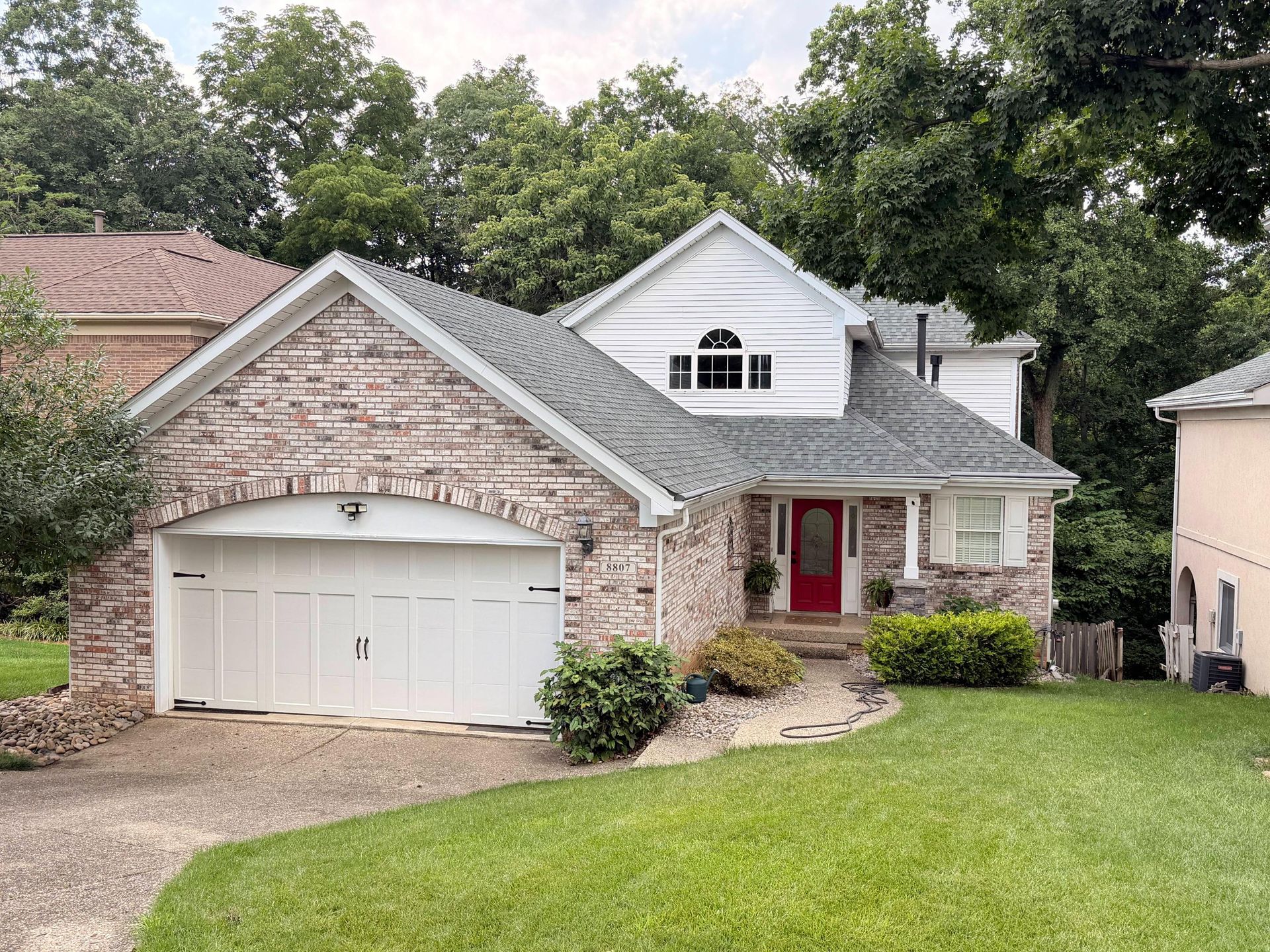 Front view of a brick home showcasing a professionally installed gray asphalt roof with matching roo 