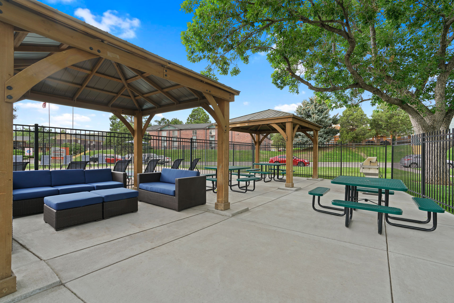 A park with a pavement, a gazebo, a bench and a table.