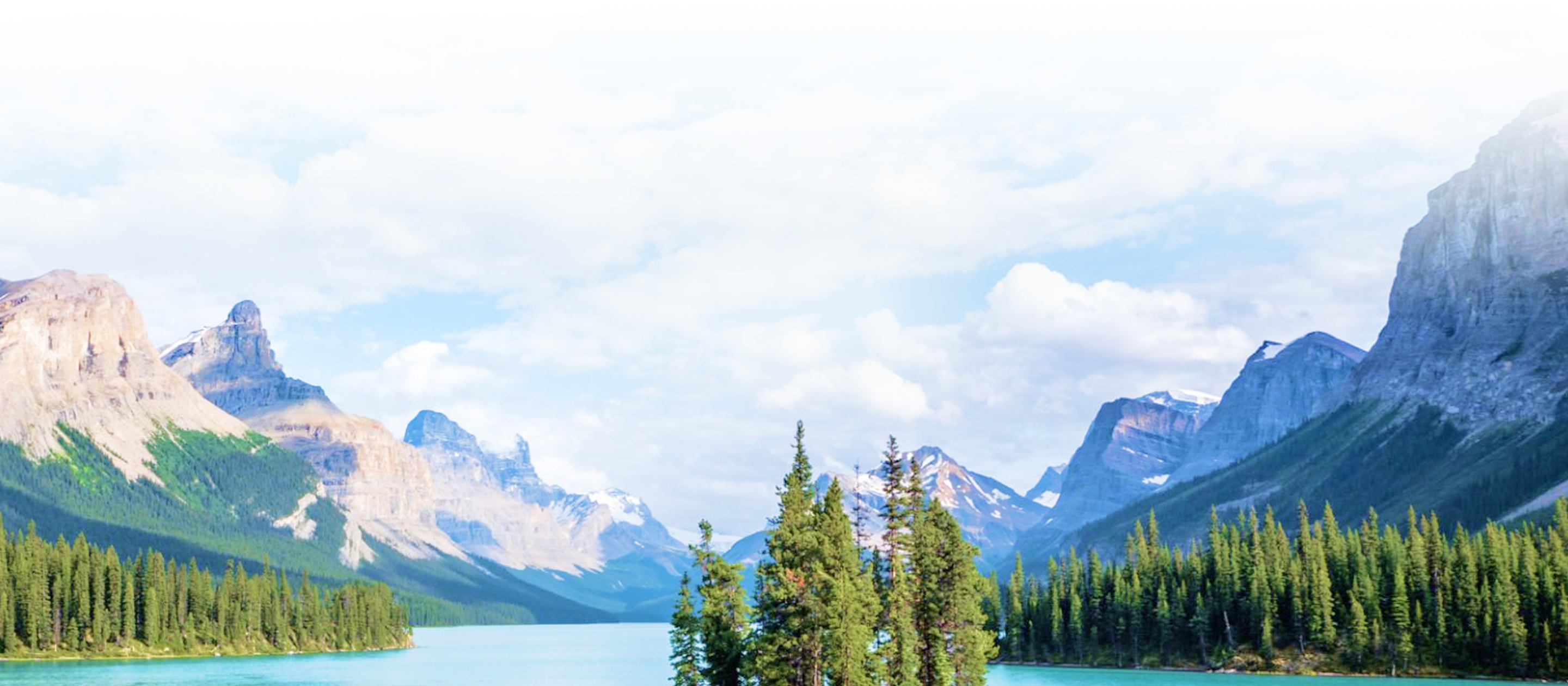 A scenic view of a lake in a valley between snow-capped mountains.