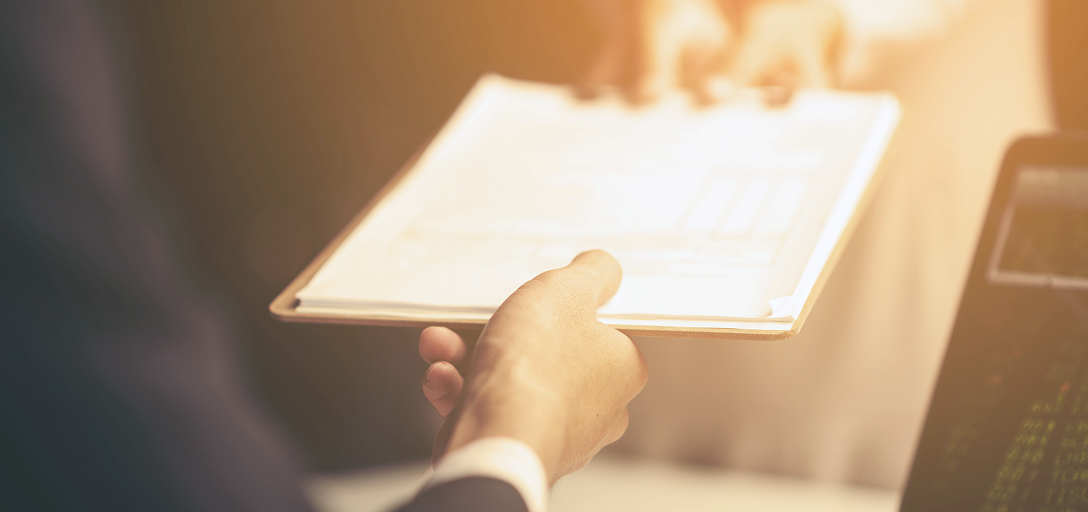 A person giving someone a printed report.