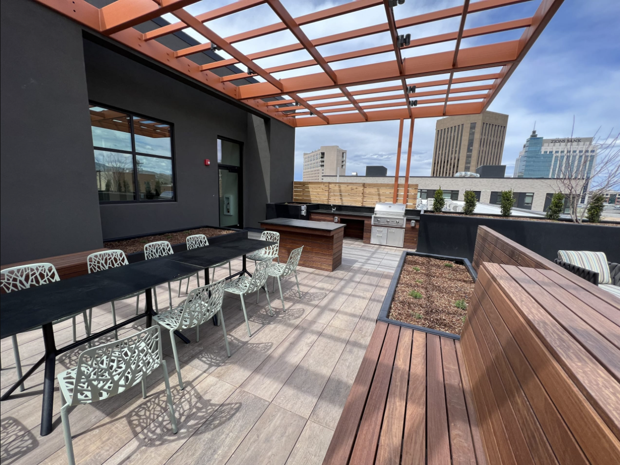 Rooftop lounge with ample seating and long table and chairs for socializing showing barbeque grills in the background