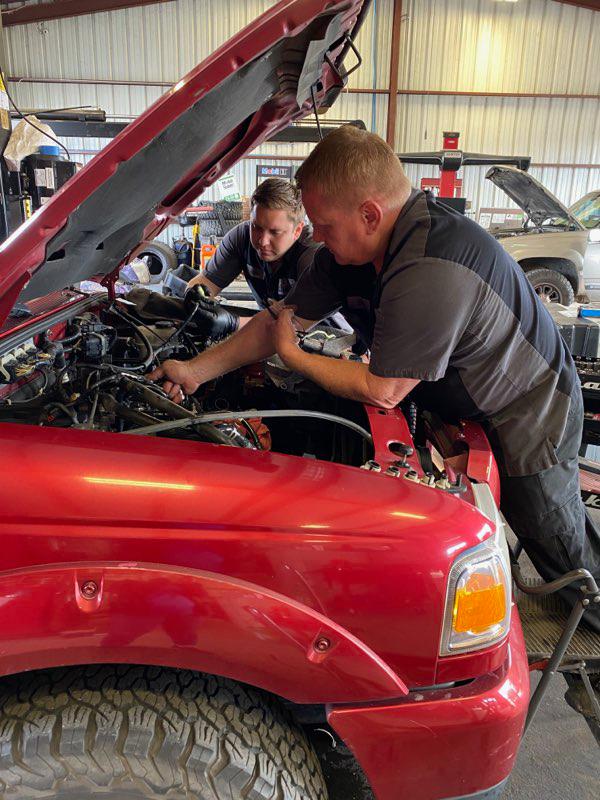 C H Auto Repair mechanics working on a vehicle.