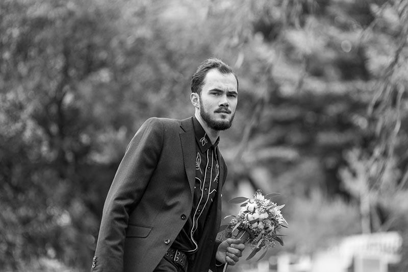 Mann in Hochzeitsanzug mit Blumen in der Hand