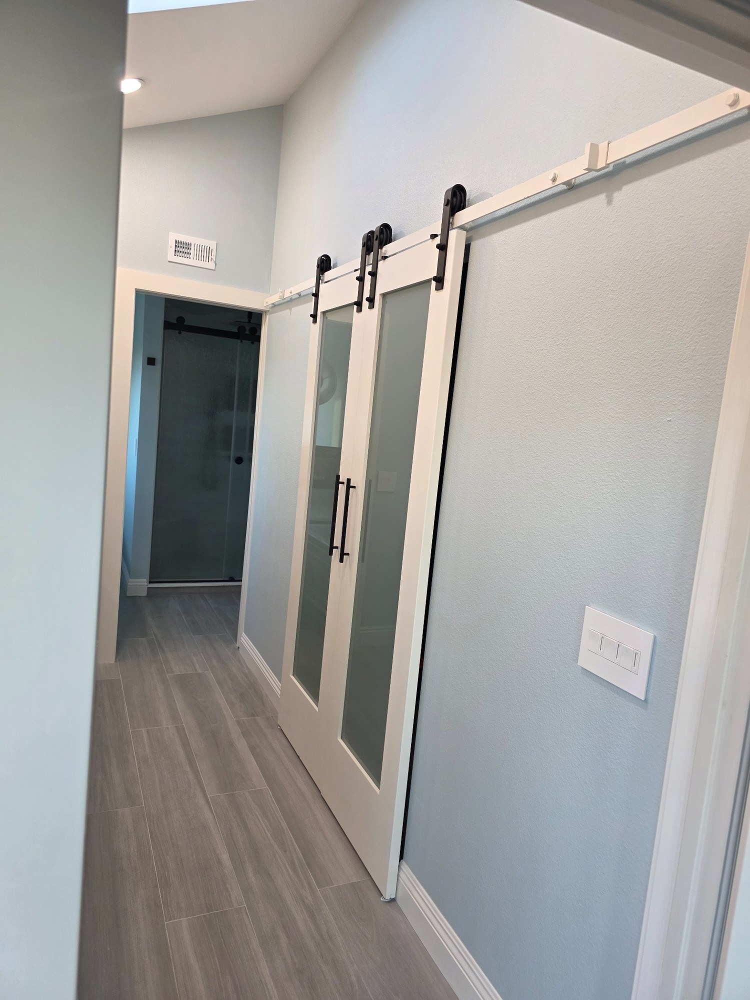 Modern interior hallway with sliding barn-style doors and wood-look flooring. 
