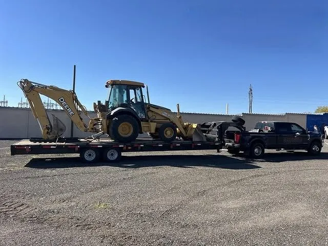 Construction backhoe loader secured on a flatbed trailer highlights heavy equipment transportation c 
