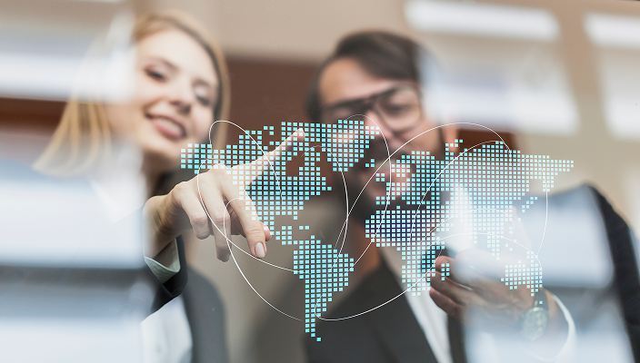 Wealth management professionals pointing at a digital projection of the world map.