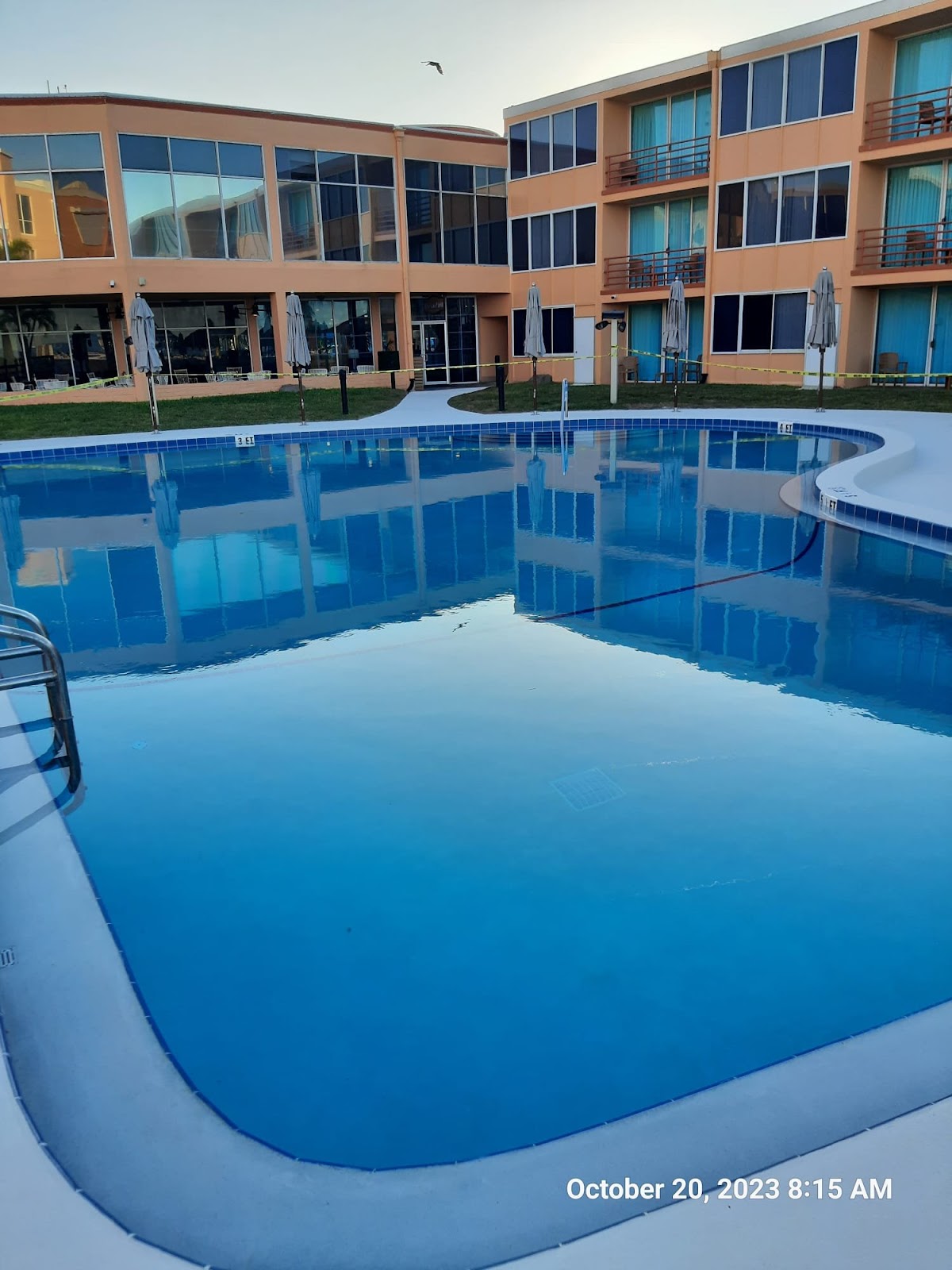 Commercial swimming pool surrounded by a multi-story residential or hotel building with a clean, well-maintained pool deck.