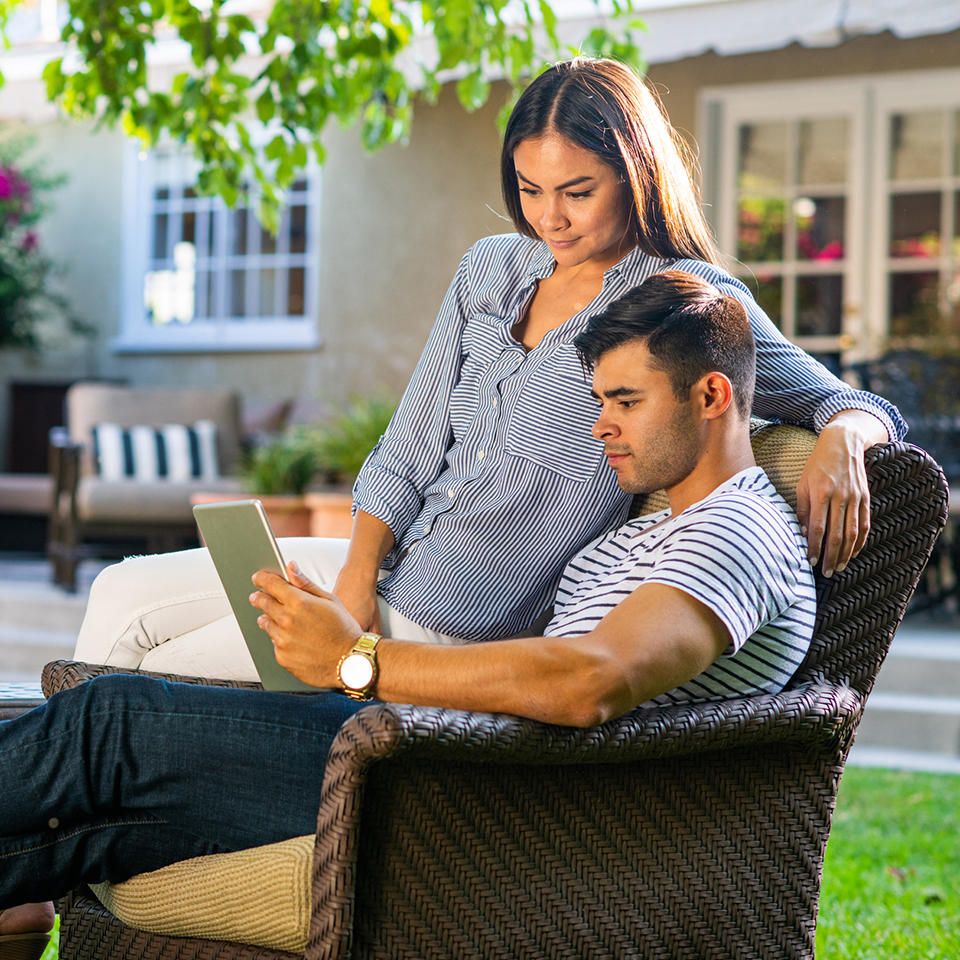 Man holding a tablet and woman sitting next to him looking at it.