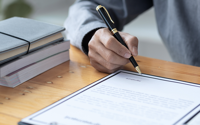 Close up of a person signing an important document.