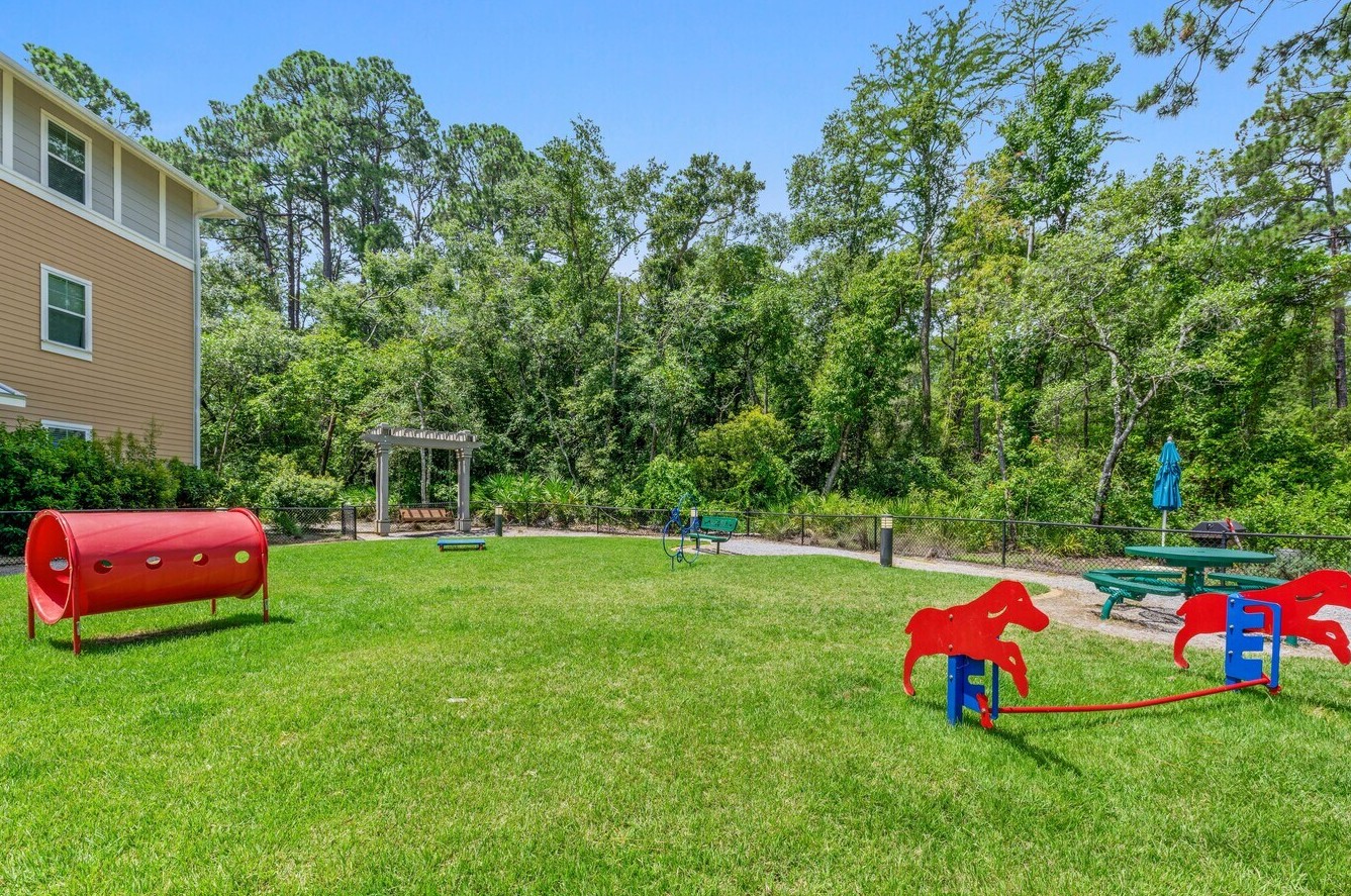 A fenced outdoor dog park with open green space and playful agility features.